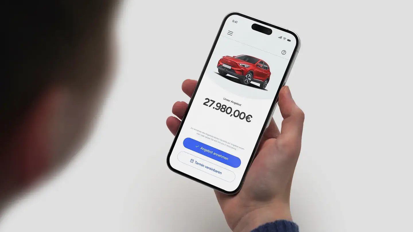 Mann vor Auto schauf auf Handy mit Kaufangebot auf Bildschirm